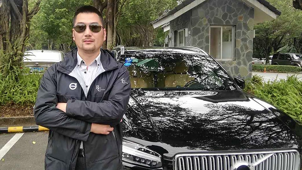 Chen Peng at standing in front of car