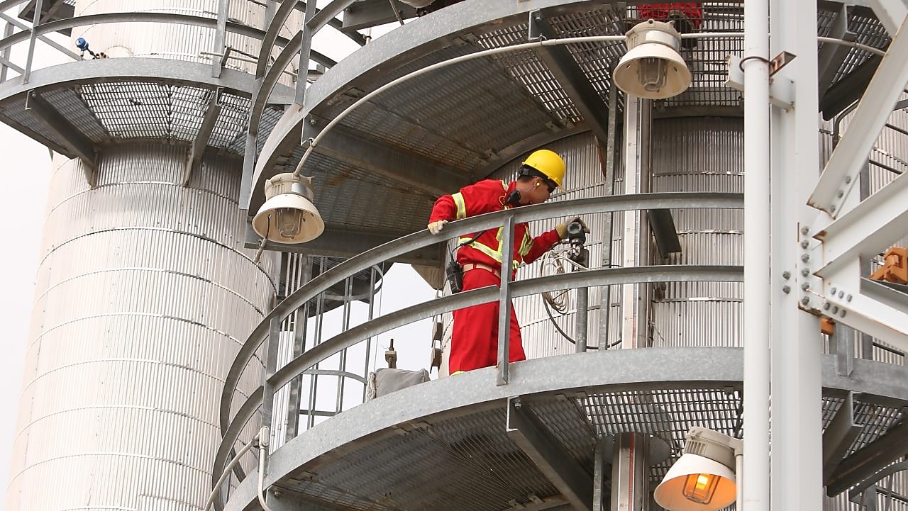 A Shell employee looks over refinery equipment from an elevated position.