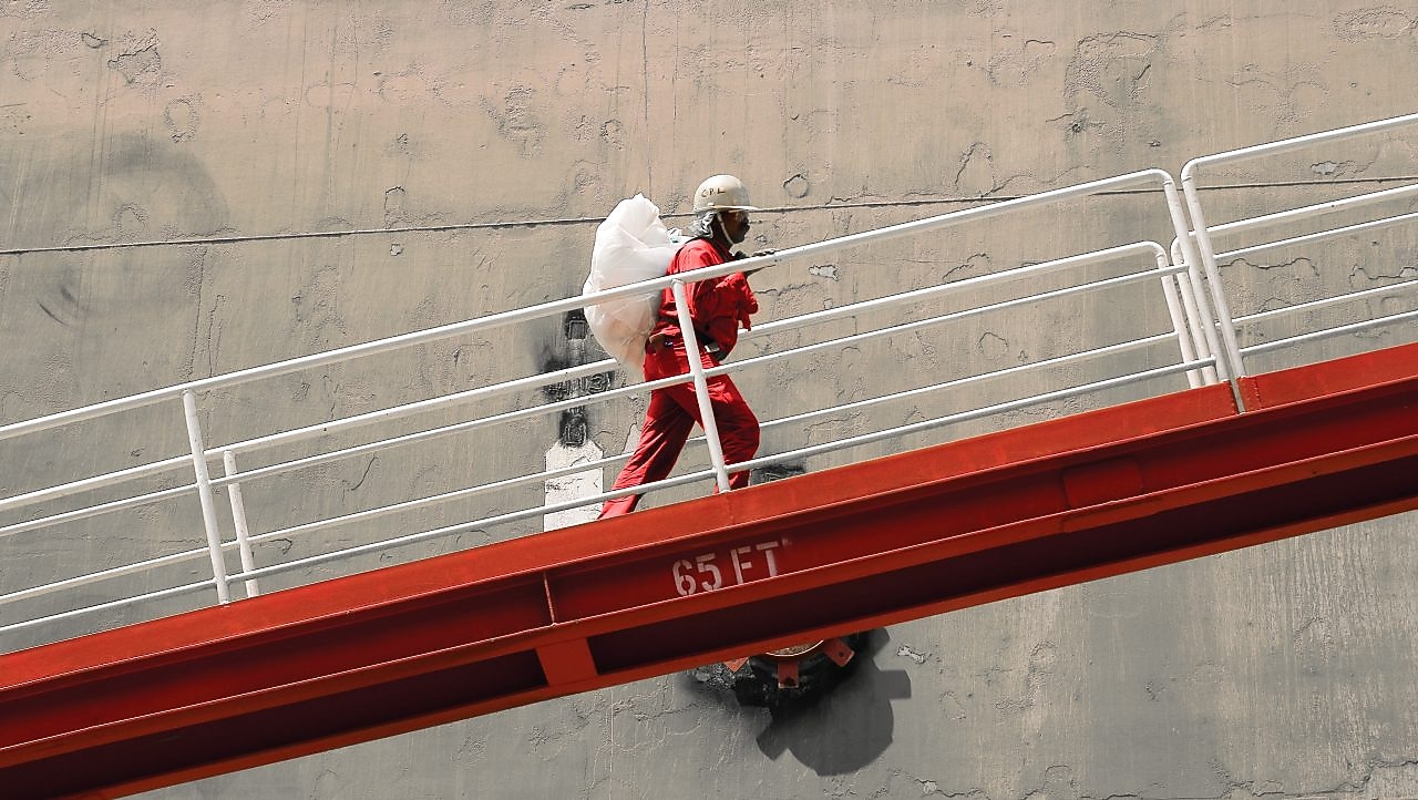 Employee climbs ramp to LNG ship.