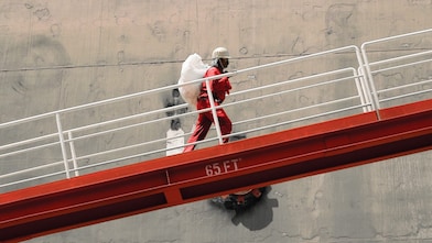 Employee climbs ramp to LNG ship.