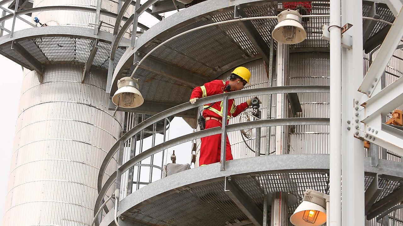 A Shell employee looks over refinery equipment from an elevated position.