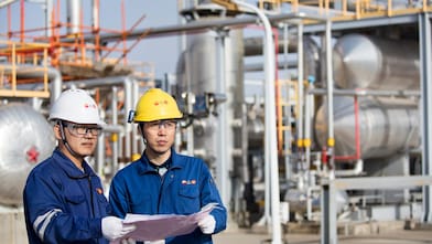 Operators reviewing refinery technology performance