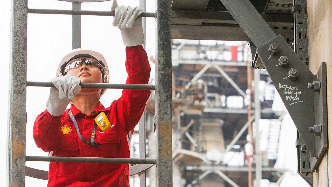 Refinery employee climbing a ladder