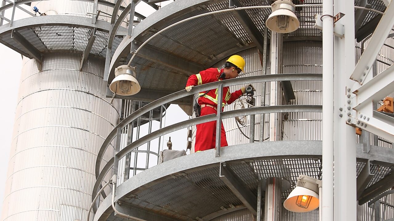 A Shell employee looks over refinery equipment from an elevated position.