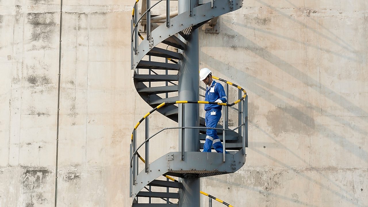 Worker descending the stairs of a LNG tank at hydrocracking facility