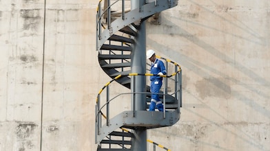 Worker descending the stairs of a LNG tank at hydrocracking facility