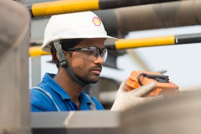 hydrotreating employee conducts routine inspection at the top of an lng tank left image