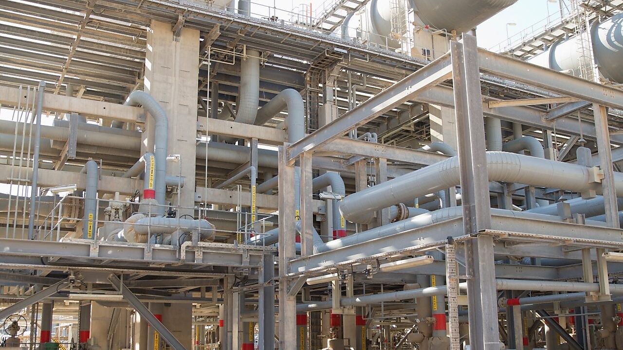 Three employees stand near a reactor with an ultra-flat quench system internal part.