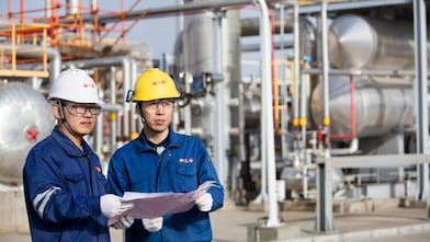 Operators reviewing refinery technology performance