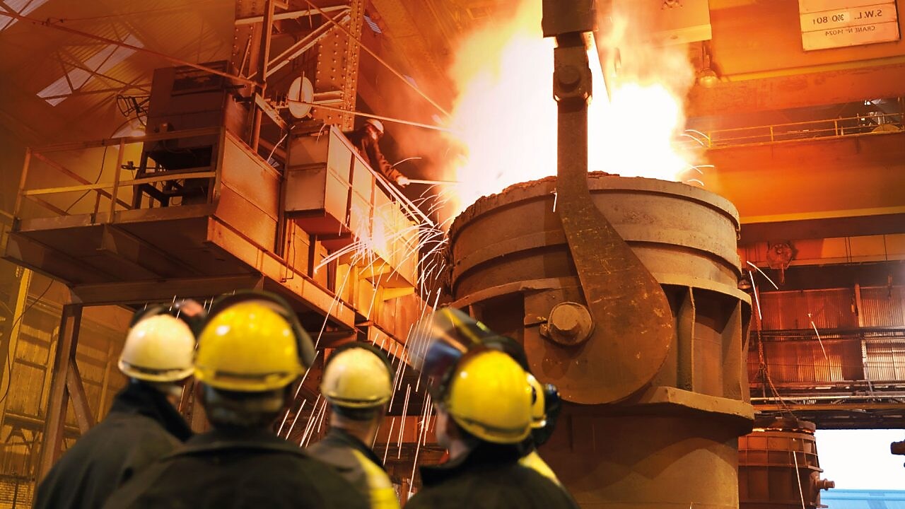 金属加工厂内关注着重型机械的工人