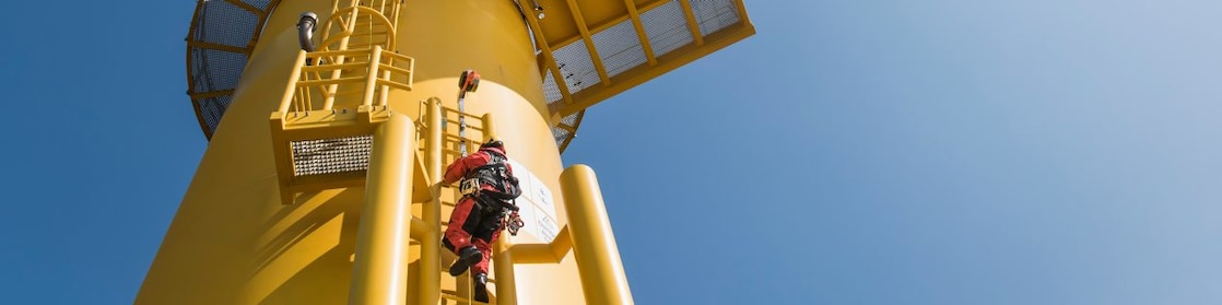 电力工程师爬上风力涡轮机进行维护。