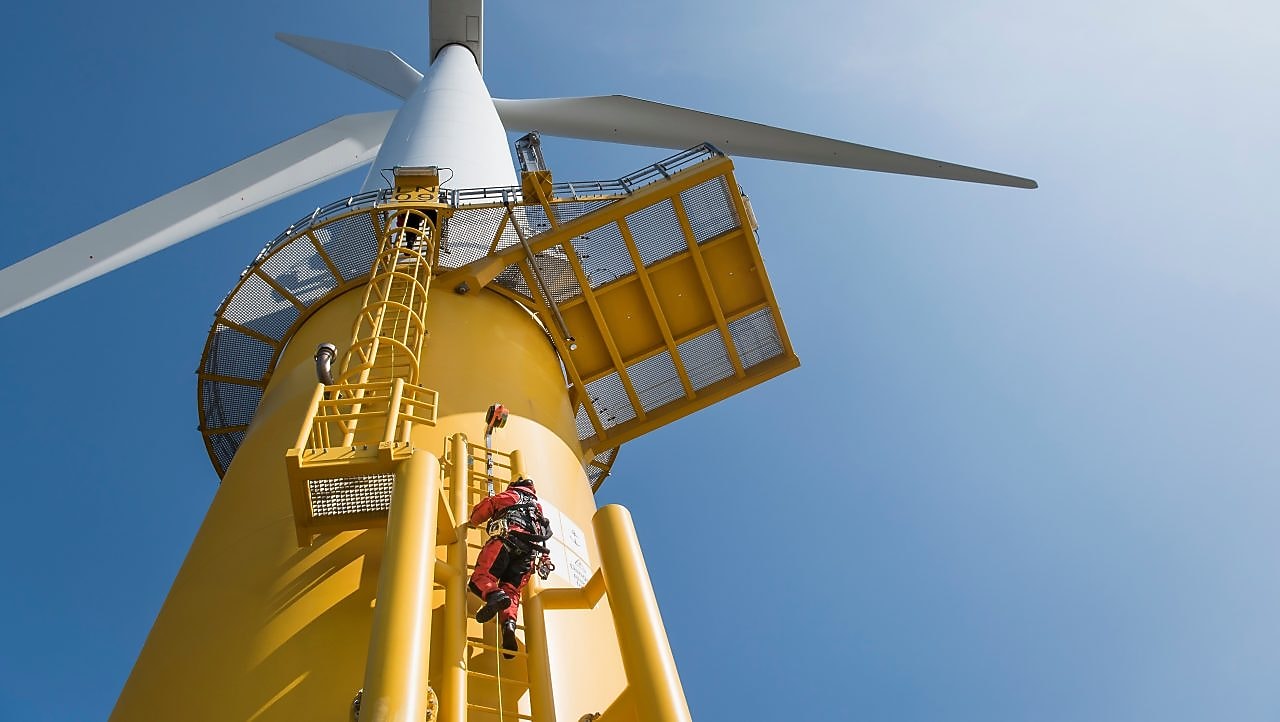 电力工程师爬上风力涡轮机进行维护。