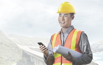 一名头戴黄色安全帽手握手机的男性