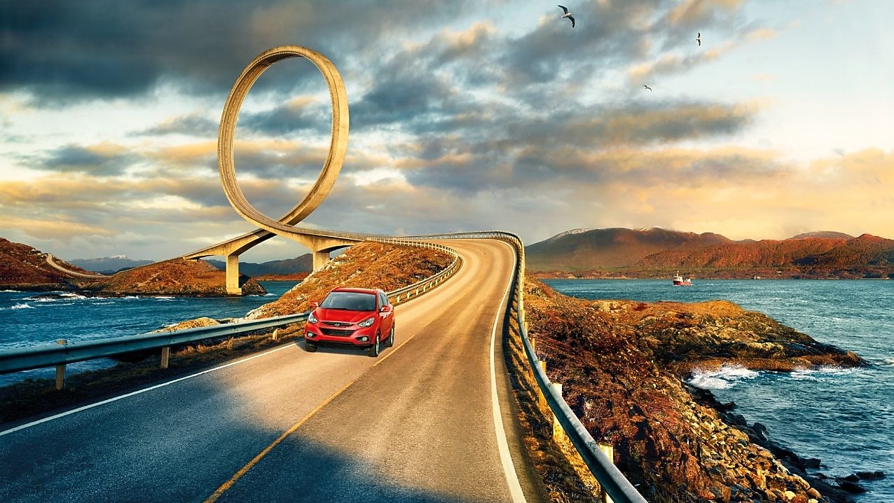 在河边公路上行驶的红色轿车