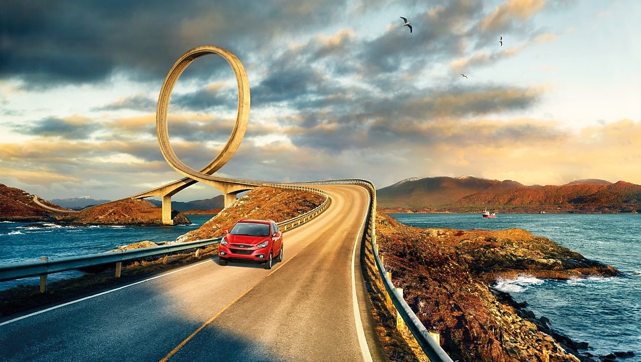 在河边公路上行驶的红色轿车