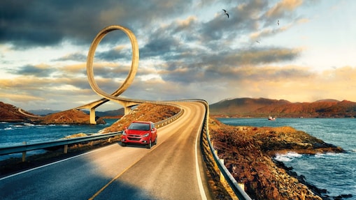 在河边公路上行驶的红色轿车