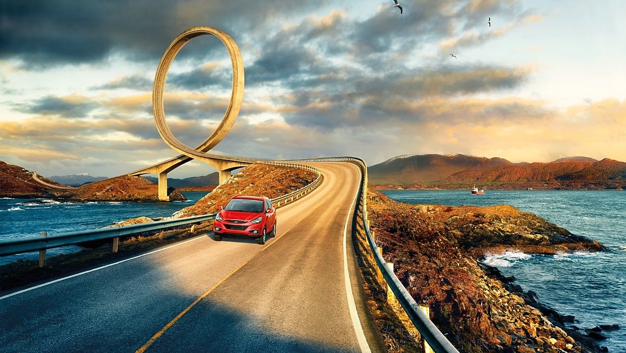 在河边公路上行驶的红色轿车