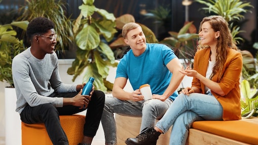 two men and a woman sitting on benches in a modern indoor space