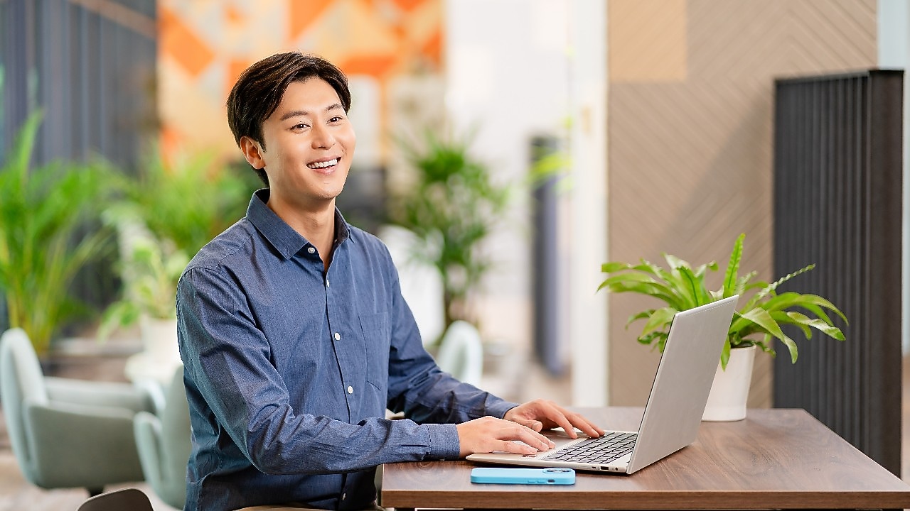 person seated at a wooden table using a laptop