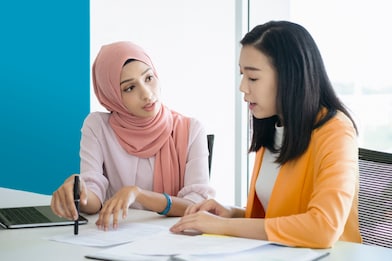 woman wearing hijab collaborating with colleague
