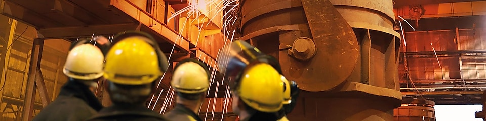 workers watching heavy machinery in a metal processing plant