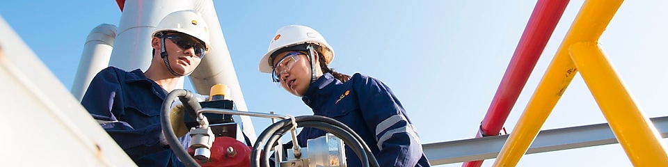 Two Shell workers standing by a pipe at the exploration and production site in Ormen Lange, Norwa