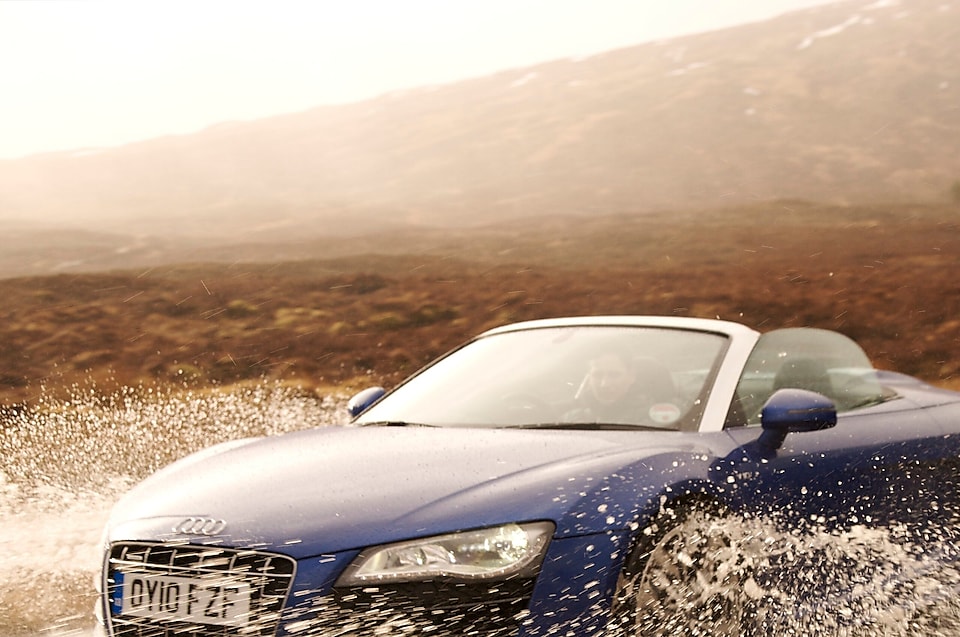 Man driving a car through a large puddle of water