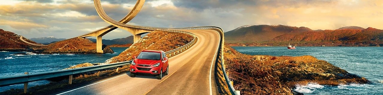 在河边公路上行驶的红色轿车