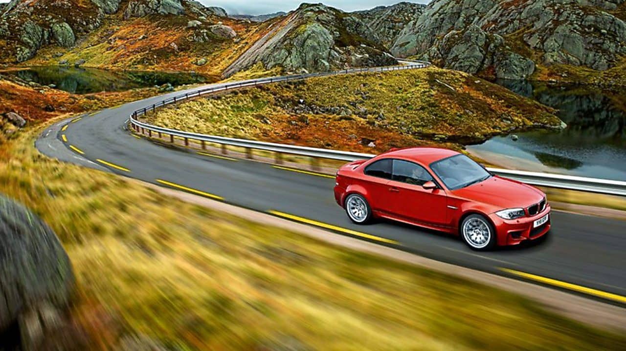 在挪威崎岖的山地公路上行驶的红色轿车