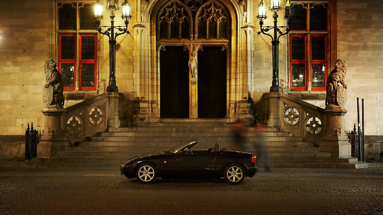 夜晚，在一些石阶旁，于一所大房子外停靠的黑色汽车