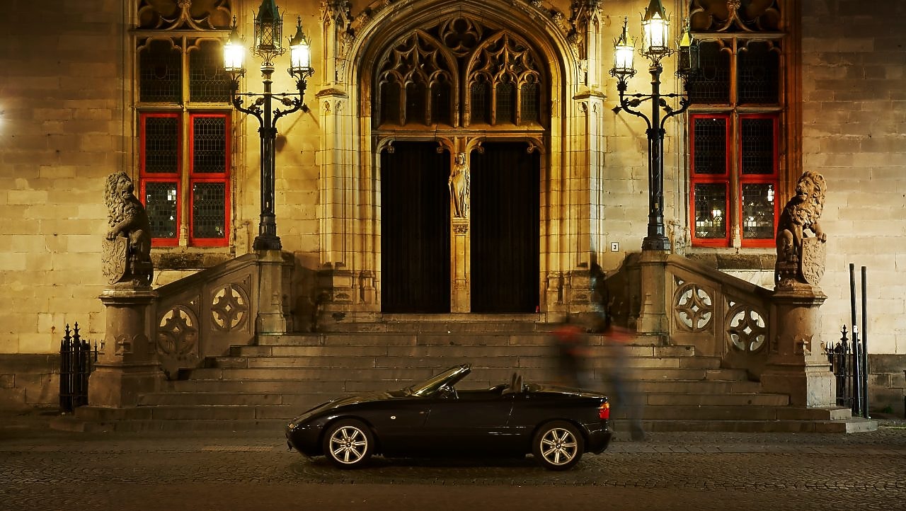 夜晚，在一些石阶旁，于一所大房子外停靠的黑色汽车