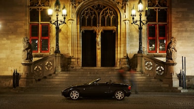 夜晚，在一些石阶旁，于一所大房子外停靠的黑色汽车