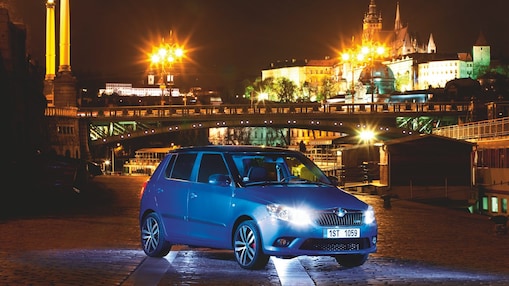 夜晚，蓝色汽车停在布拉格的道路上，远处是一座桥和城堡