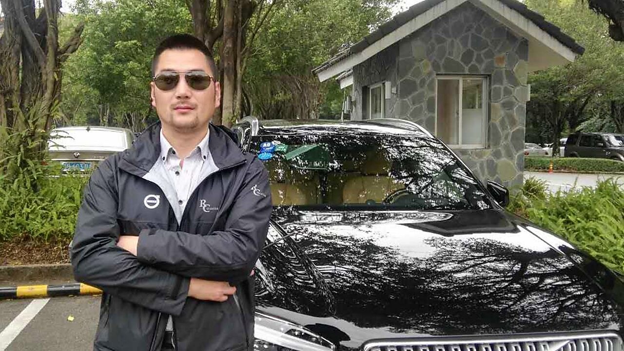 Chen Peng at standing in front of car