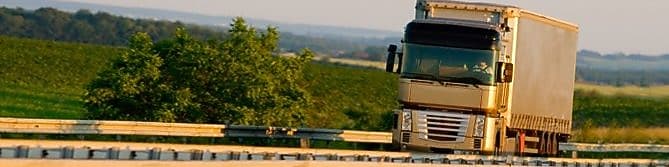 绿意盎然的乡村风景下,在公路上行驶的卡车