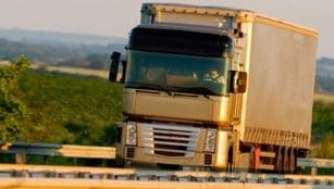 绿意盎然的乡村风景下，在公路上行驶的卡车