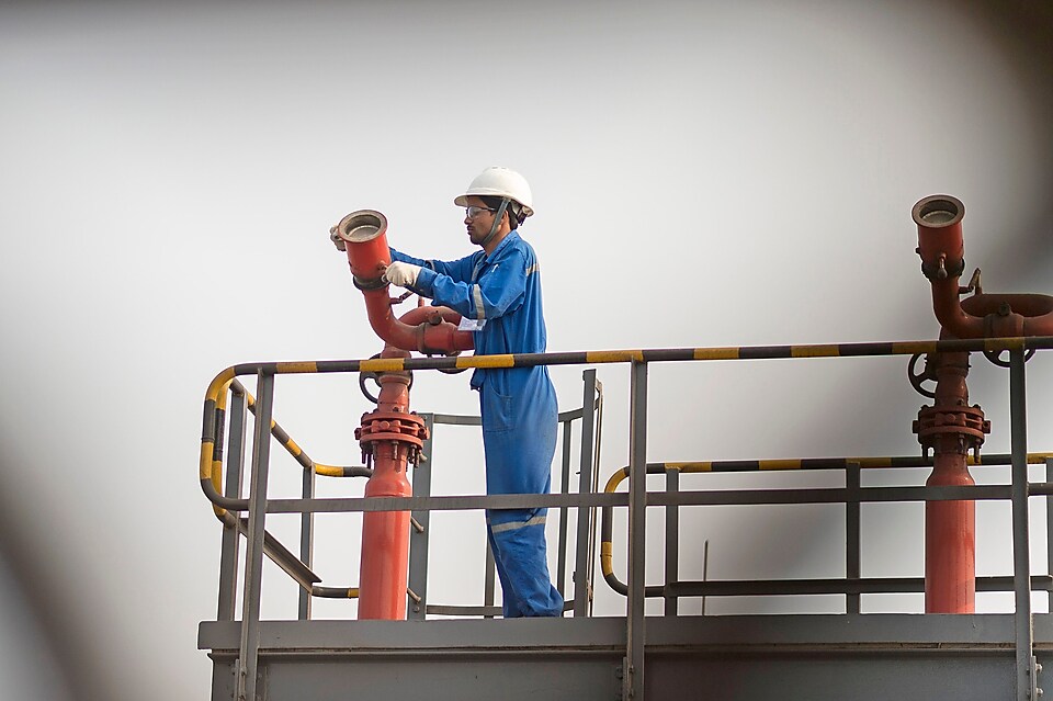 A worker adjusts equipment used in a fluidised catalytic cracking facility